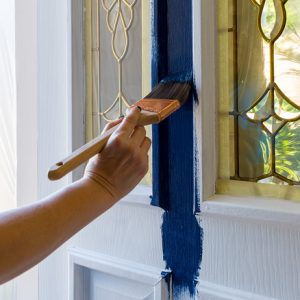 Brush painting house front door with blue paint at home do it yourself project Female hand holding Brush painting house front door with blue paint at home do it yourself project